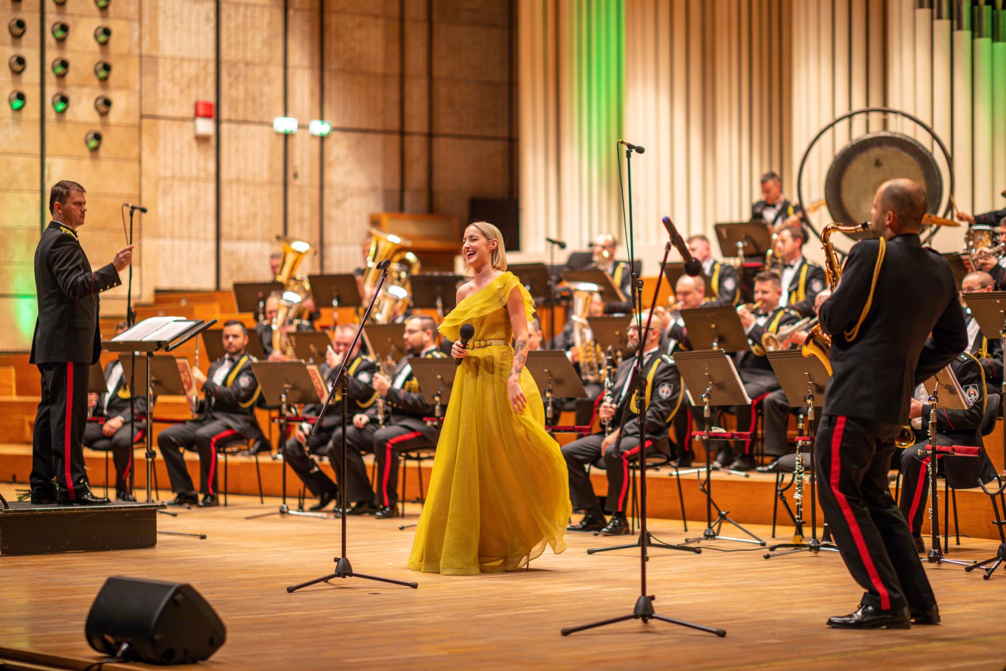 Lenka Piešová v slávnostných šatách, usmiata a spievajúca s orchestrom